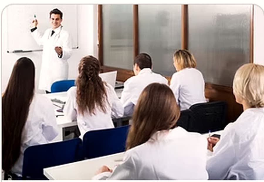 An instructor leading a CPR and First Aid certification class in a training room.
