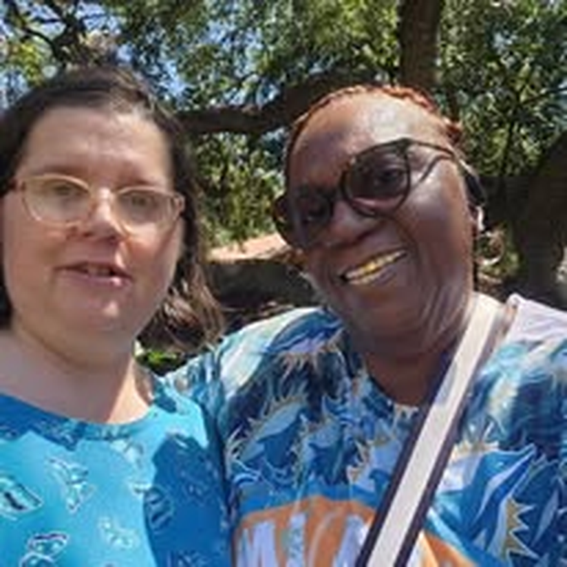 Two staff members smiling together outdoors during a community outing.