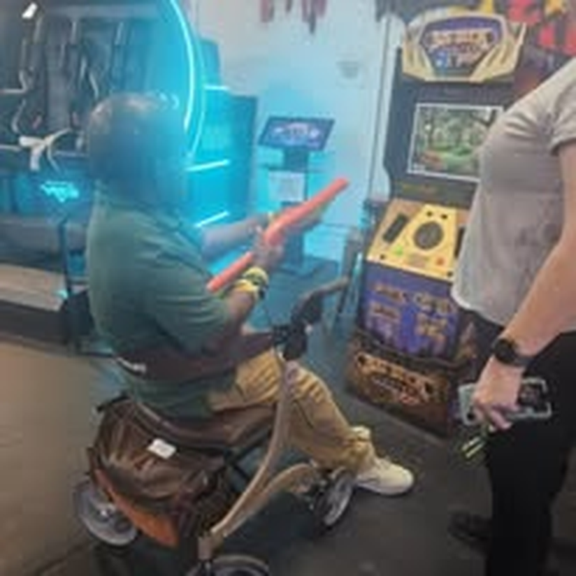 An individual in a wheelchair playing a racing game at the arcade.