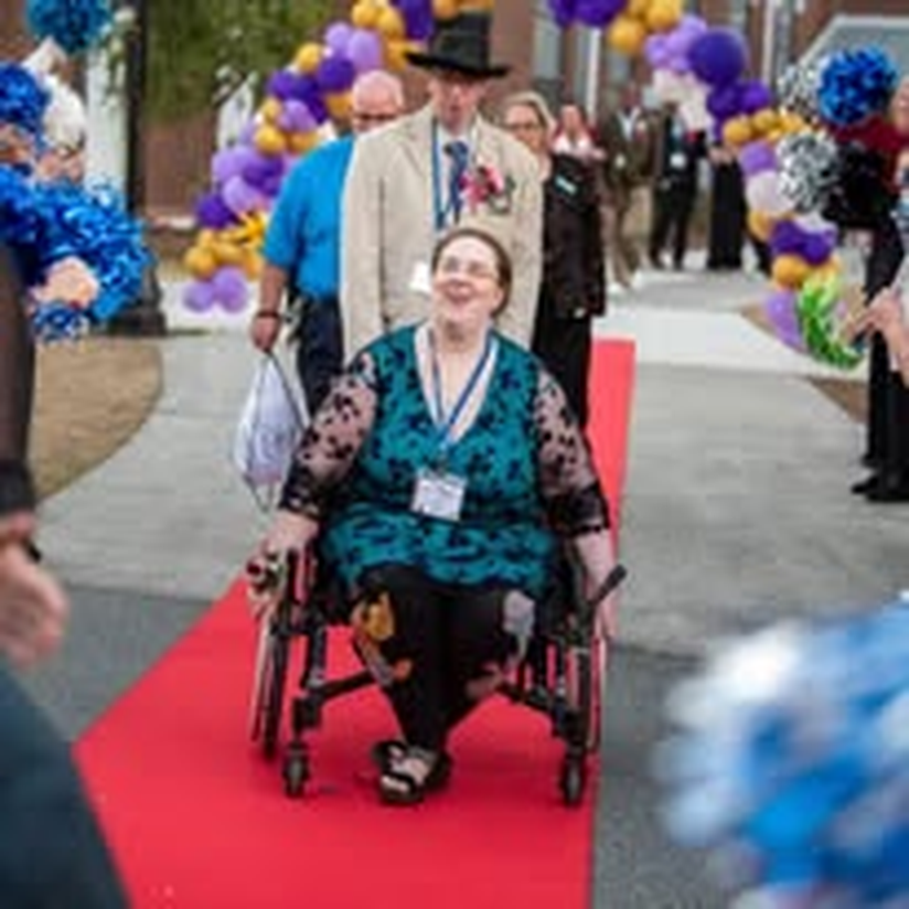 An individual in a wheelchair with a medal, proud on the red carpet.