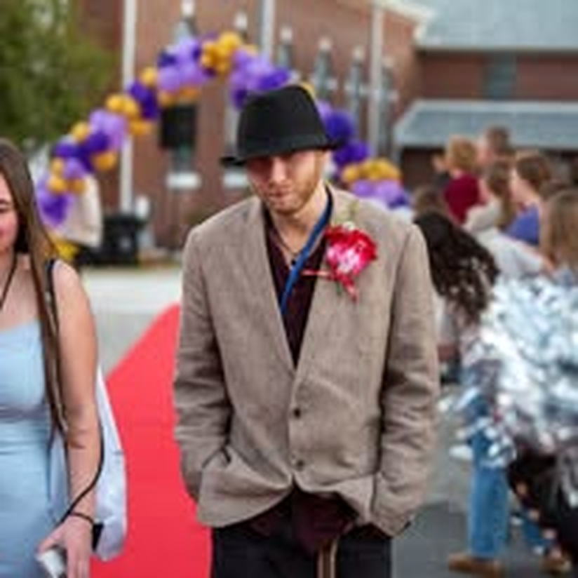 A young couple dressed up in gala attire, top hat and all.