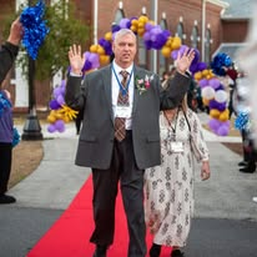 An individual waving to the crowd on the red carpet.