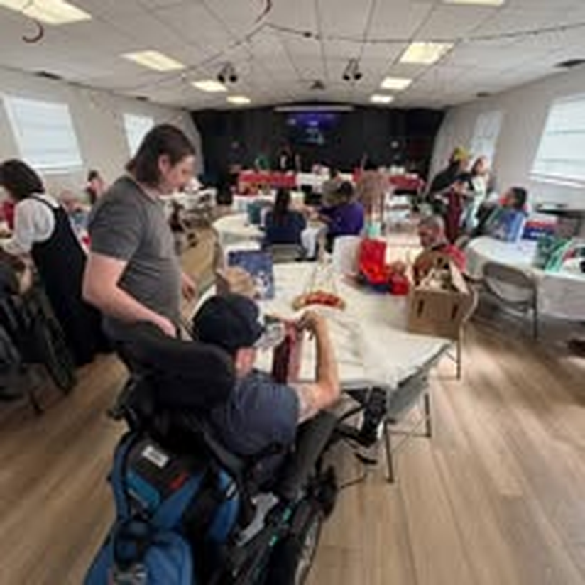An individual in a wheelchair lending a hand at a holiday gift-wrapping event.