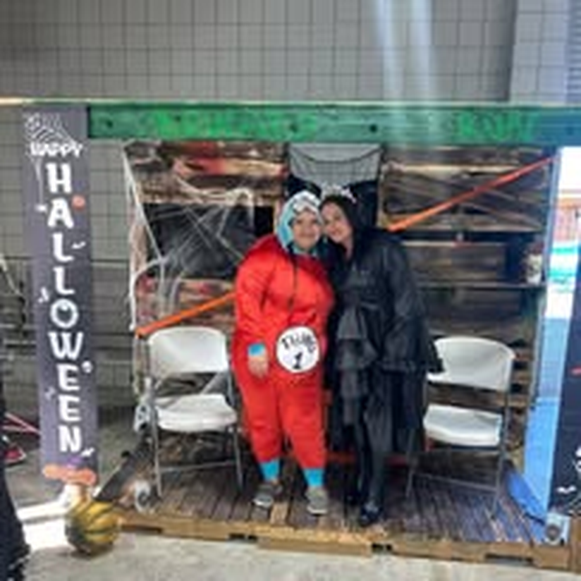 Two people in costume posing at the Halloween photo booth.
