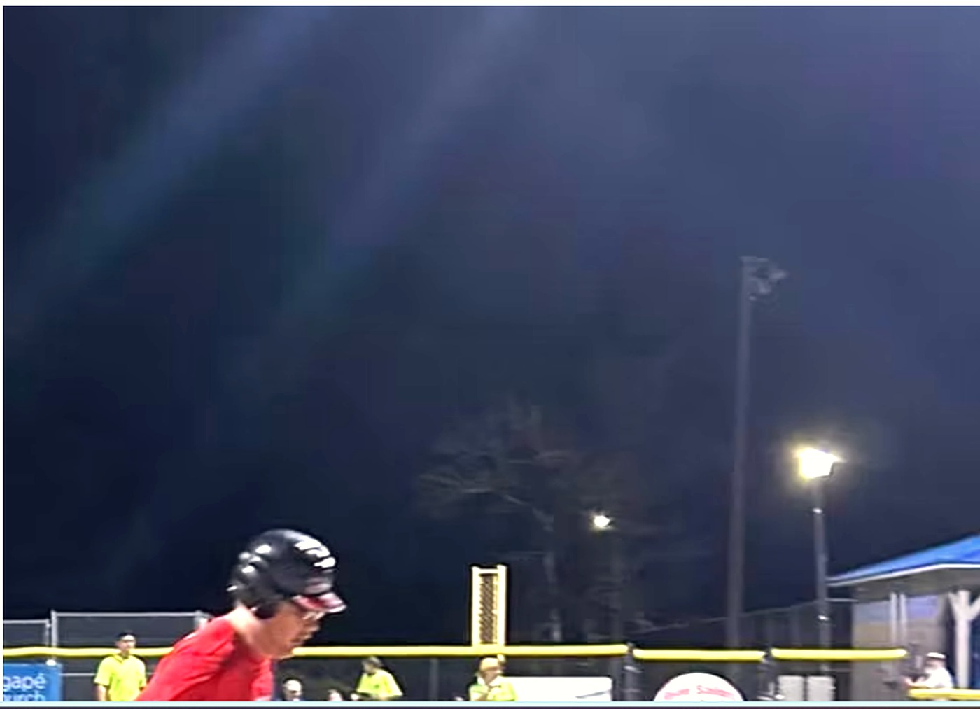 An SIWD athlete at bat under the floodlights during an evening softball game.