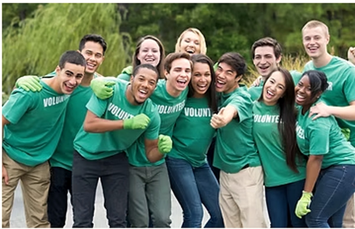 A group of SIWD volunteers in matching shirts, arm in arm and cheering.